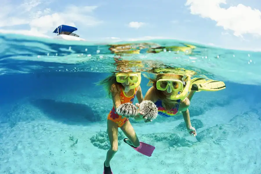 hula hula island tour - two girls wearing snorkeling gear and flippers in the water